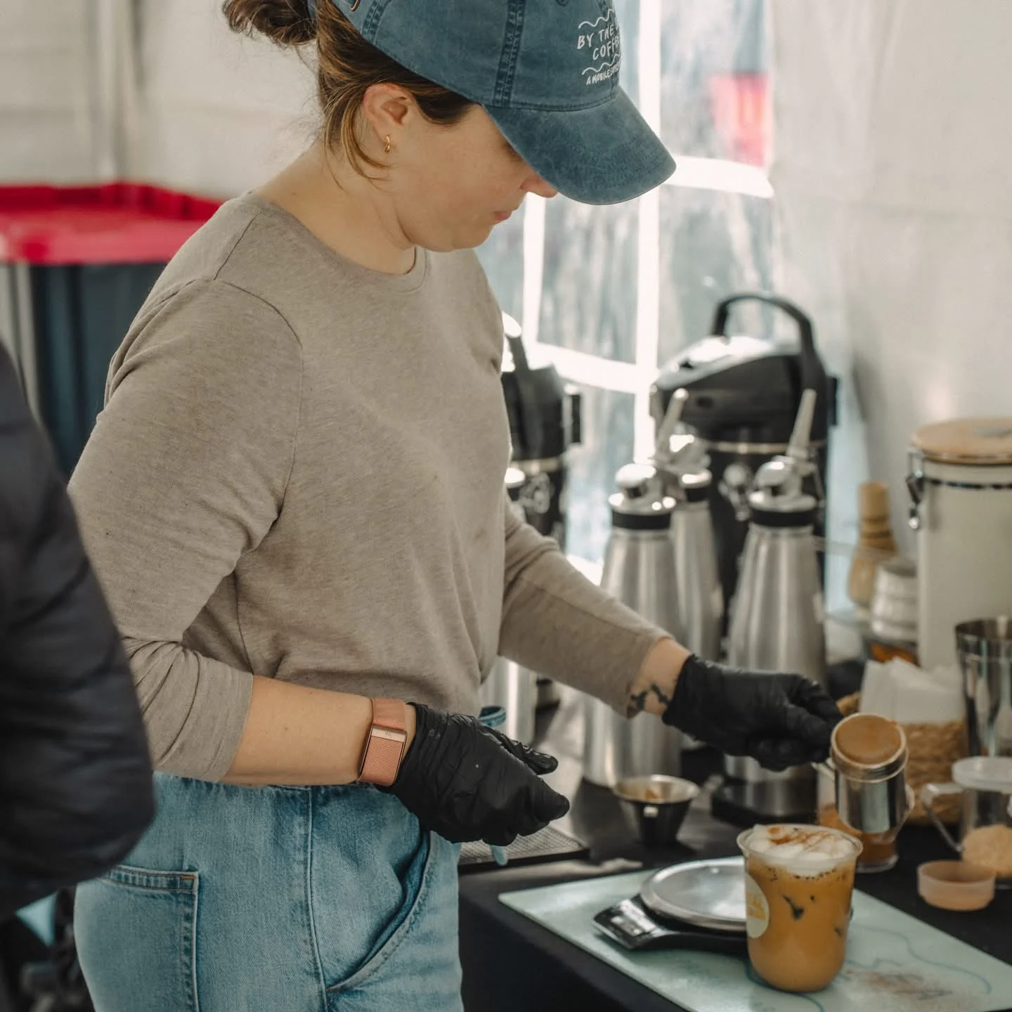Emily preparing a branded iced coffee inside the By the Sea Coffee mobile espresso bar