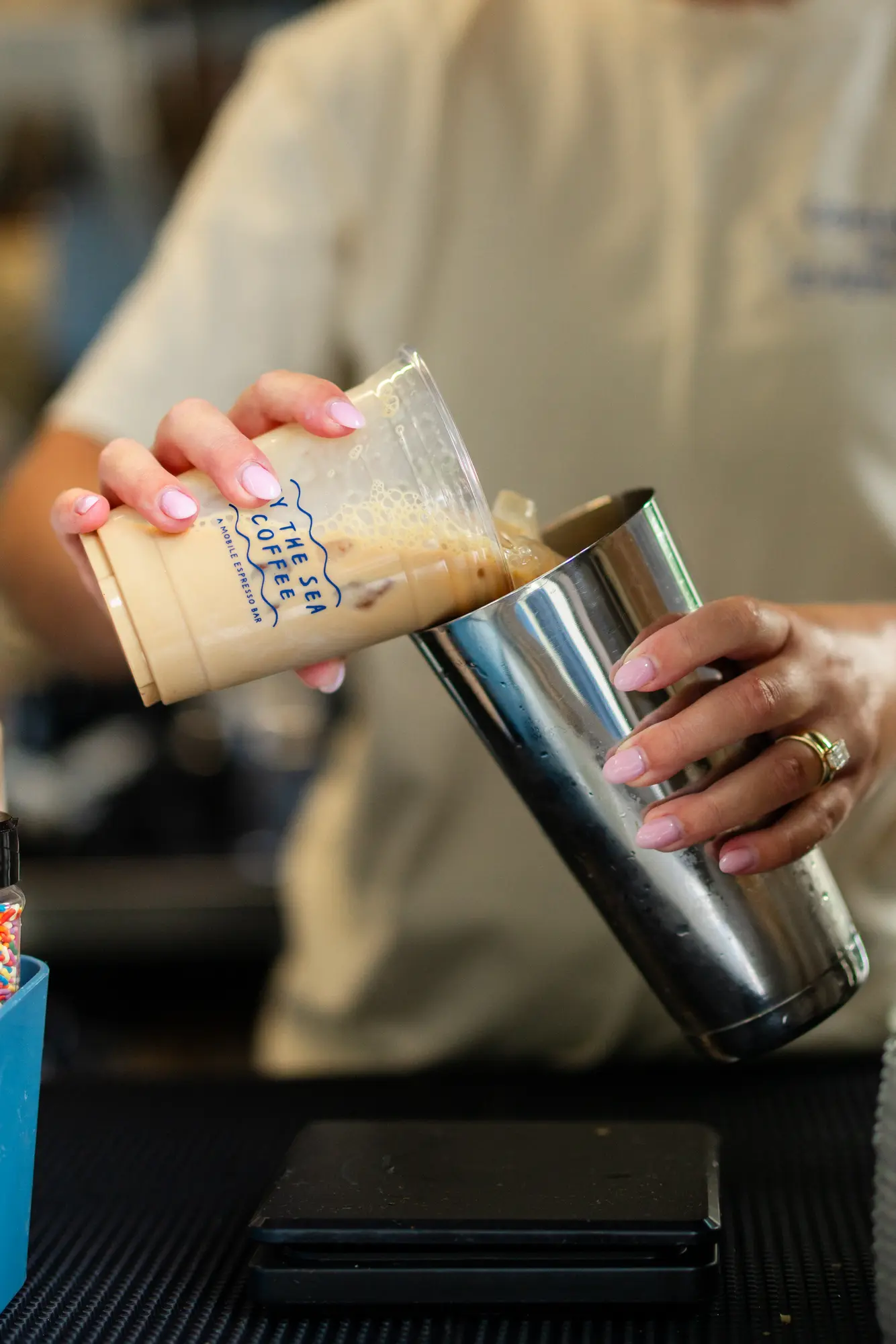 A By the Sea Coffee barista measuring an iced drink during service